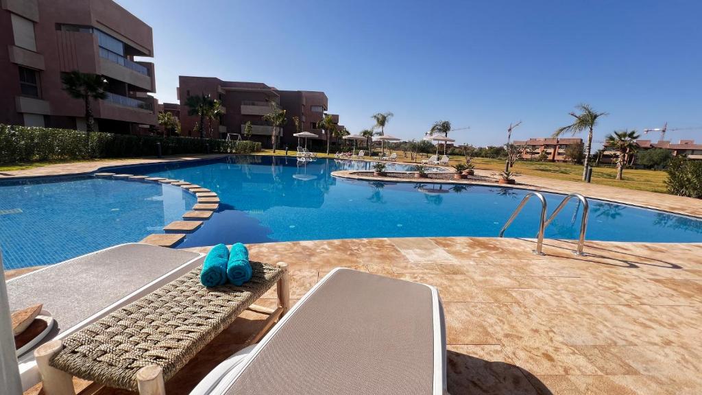 una piscina con un banco frente a ella en Prestigia,Golf, piscine, soleil, paysage, sport, spacieux,lux résidence en Marrakech