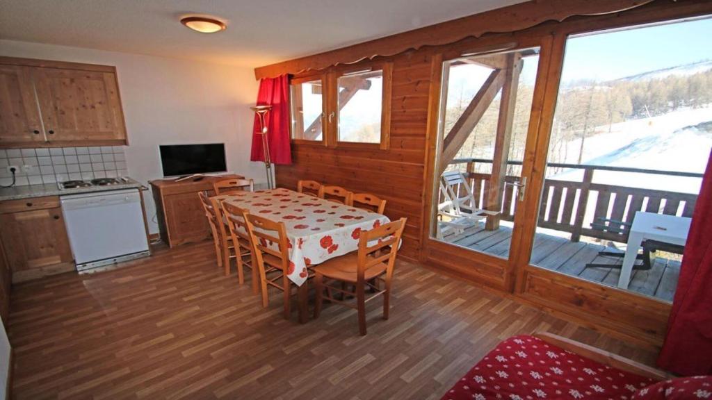 une cuisine et une salle à manger avec une table et un balcon dans l'établissement Résidence Hameau Des Ecrins - HEC112 - APPARTEMENT 6 PERSONNES, SECTEUR 1700M MAE-8994, à Narreyroux