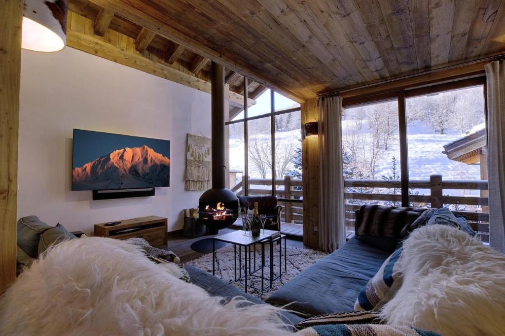 a living room with a couch and a tv at Chalet Hygge - Chalets pour 12 Personnes 004 in Les Allues