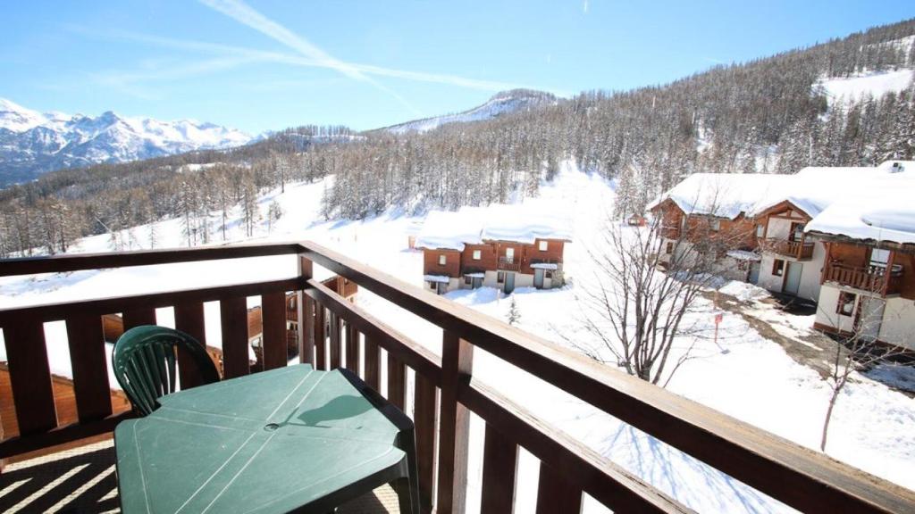 un balcone di legno con un tavolo e montagne innevate di Résidence Parc Aux Etoiles - C310PAE - APPARTEMENT 2 CHAMBRES AVEC BALCON MAE-8774 a Narreyroux