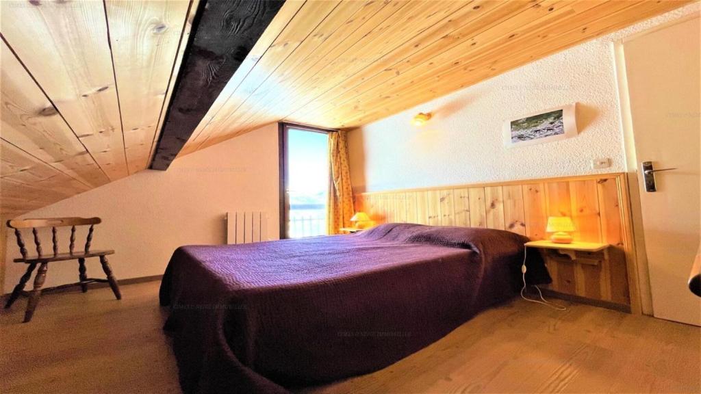 Un dormitorio con una cama grande y una ventana en Résidence Les Soldanelles - Appartements pour 6 Personnes 134, en Puy-Saint-Vincent