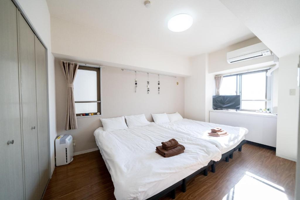 a white bedroom with a large white bed in it at Nishinippori Guest House in Tokyo