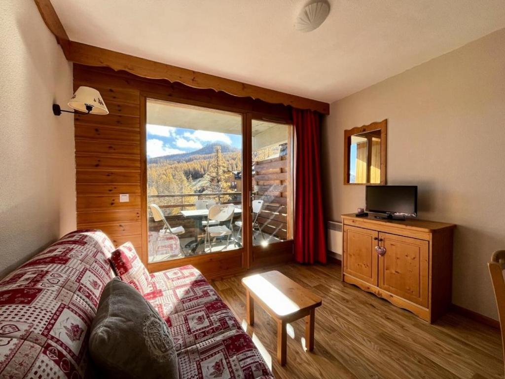 a living room with a couch and a large window at Résidence Hameau Des Ecrins - 2 Pièces pour 4 Personnes 014 in Narreyroux
