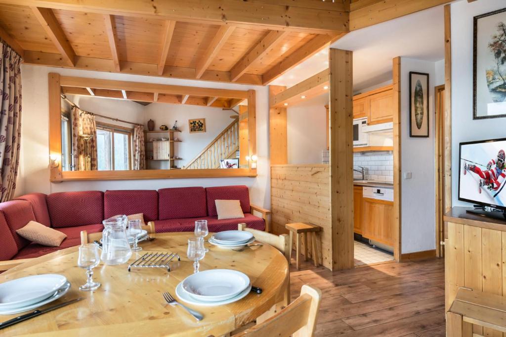 a dining room and living room with a wooden table at Résidence Les Cimes Blanches - Studio pour 5 Personnes 494 in Courchevel