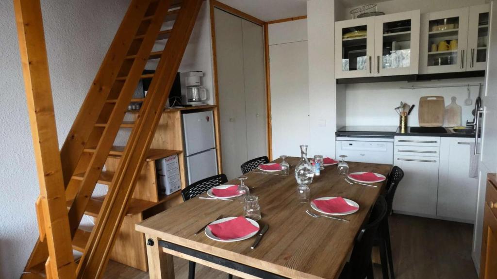 une table en bois avec des assiettes rouges et des verres dans l'établissement Résidence CHEVAL BLANC - 3 Pièces pour 6 Personnes 64, à Valmorel