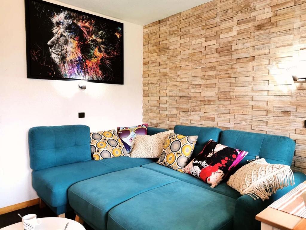 - un canapé bleu dans un salon avec un mur en briques dans l'établissement Résidence Cheval Blanc - Le Cheval Blanc B2 - Agréable 2 pièces, vue magnifique sur la vallée MAE-7324, à Valmorel