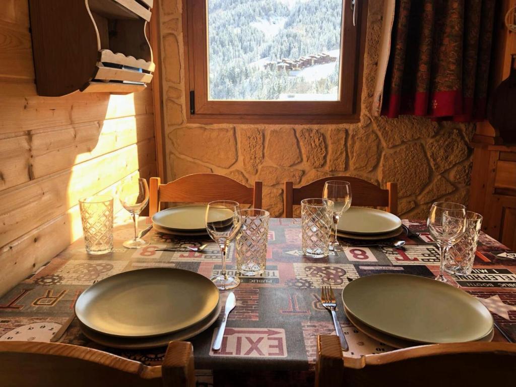 une table avec des assiettes et des verres au-dessus dans l'établissement Résidence Clairiere - La Clairière 2 - Joli studio avec magnifique vue sur la station MAE-4334, à Valmorel