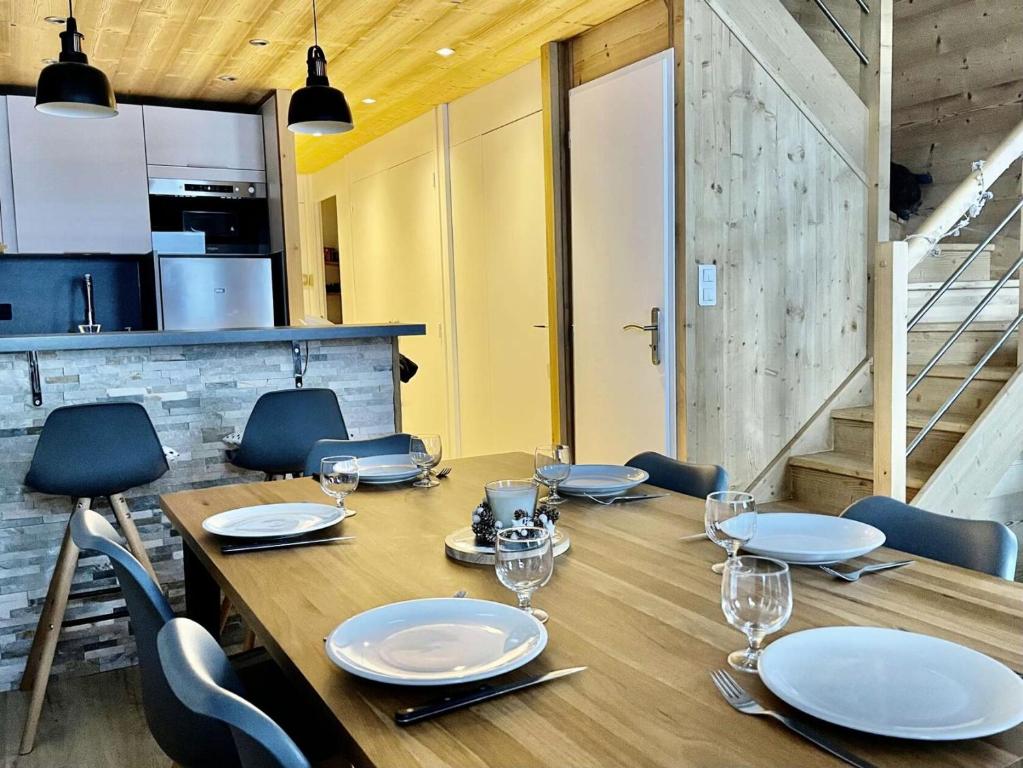 - une table en bois avec des chaises et des assiettes dans l'établissement Résidence Lauzes - Les Lauzes 43 - Magnifique duplex, moderne et chaleureux MAE-4034, à Valmorel