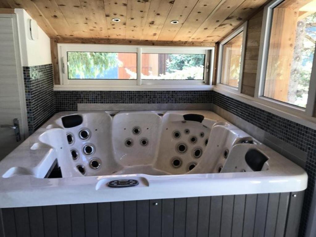 una grande vasca in un bagno con due finestre di Résidence Regain - Chalets pour 6 Personnes 464 a Vars