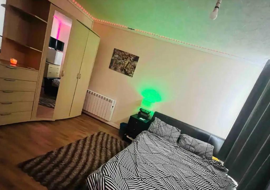 a bedroom with a bed and a green lamp at House in Peterborough