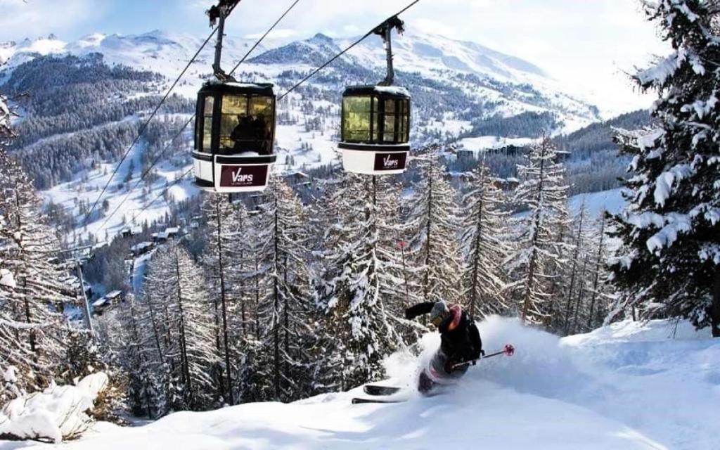 a person skiing down a snow covered slope under a ski lift at Résidence Centre Vars - Studio pour 3 Personnes 914 in Vars