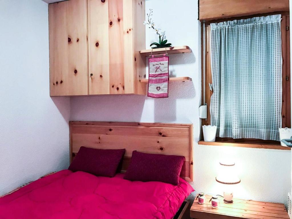 een slaapkamer met een bed met roze lakens en een raam bij Résidence Grande Chaume - 2 Pièces pour 4 Personnes 344 in Vénosc