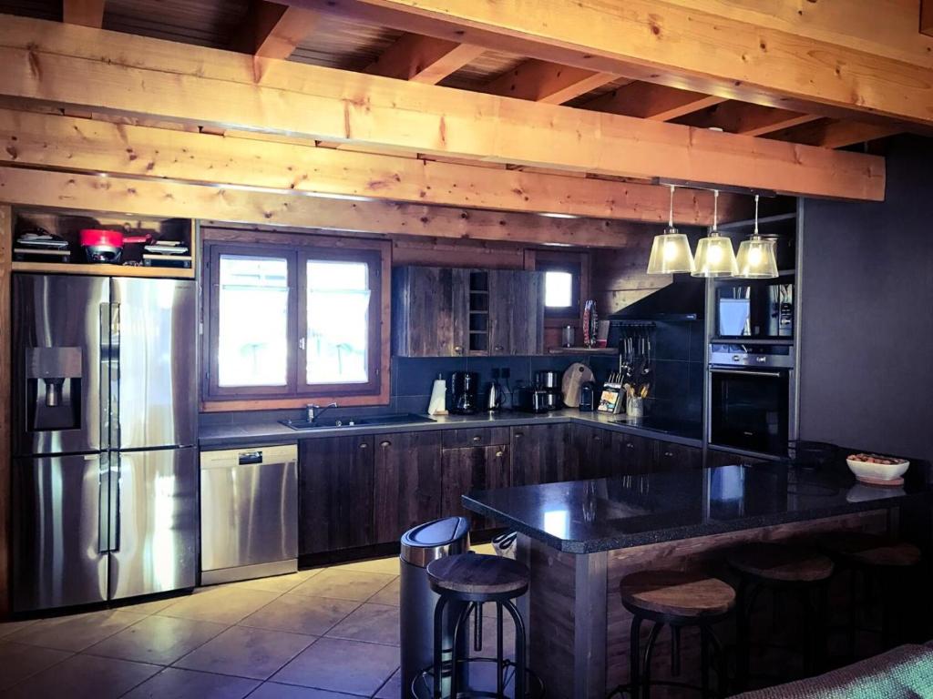 a kitchen with a refrigerator and a counter with stools at Chalet Gaspard - Chalets pour 16 Personnes 494 in Vénosc