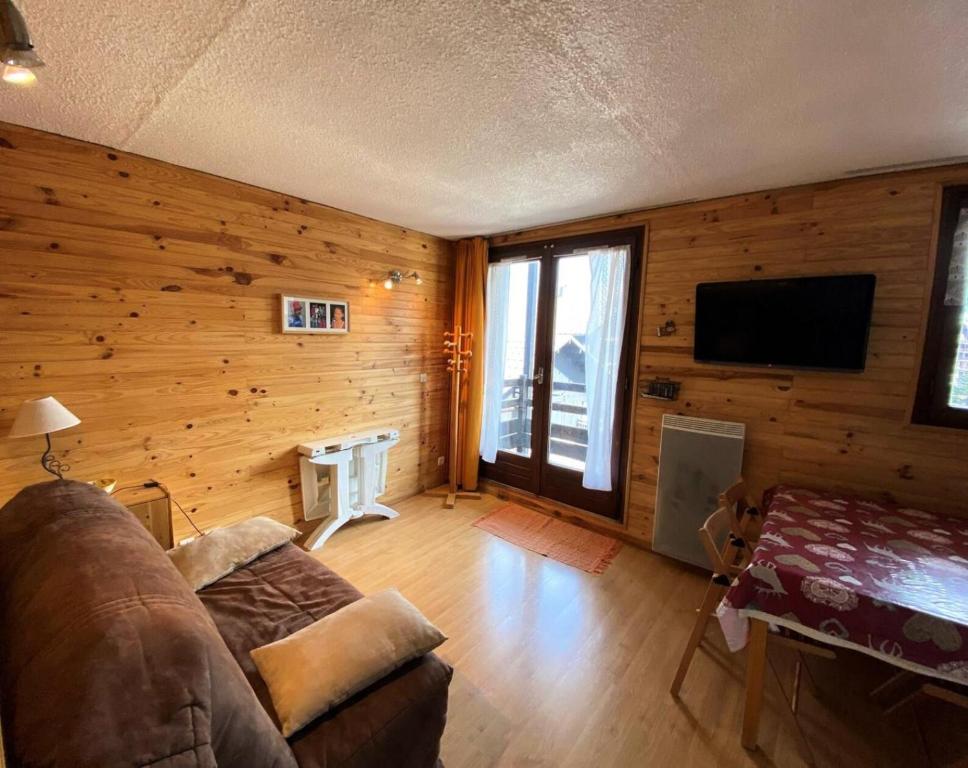 ein Wohnzimmer mit Holzwänden, einem Sofa und einem TV in der Unterkunft Résidence Airelles A - 2 Pièces pour 4 Personnes 424 in Risoul