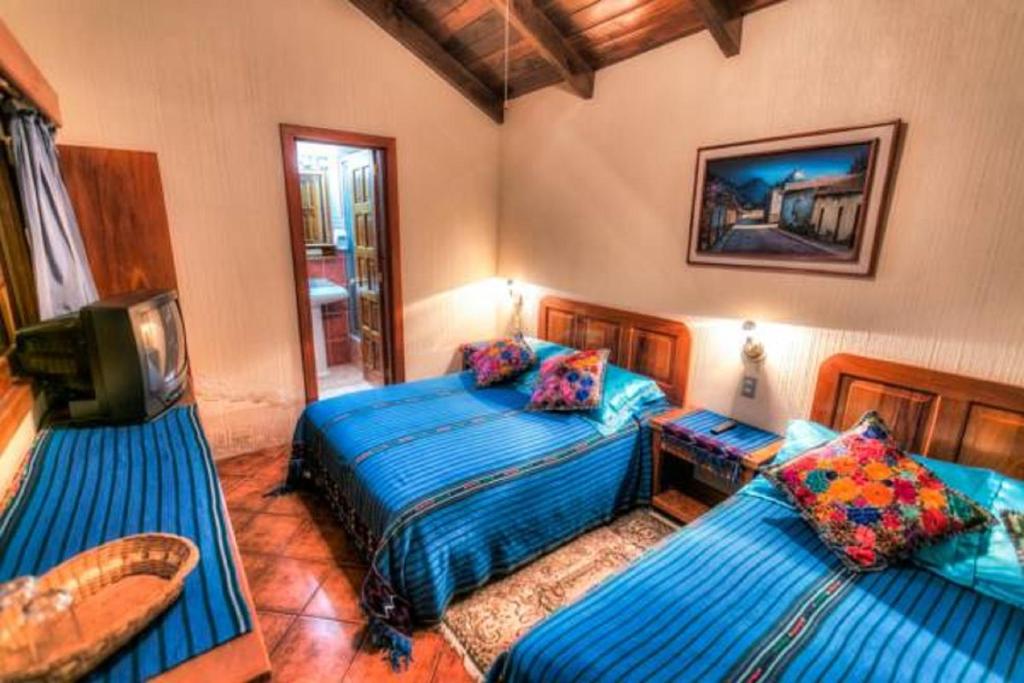 a bedroom with two beds and a tv in it at Posada De Los Volcanes in Panajachel