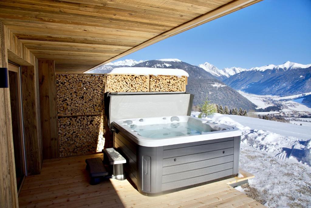 a hot tub on a deck with mountains in the background at Rueper Hof Chalet Ruipa in Valdaora