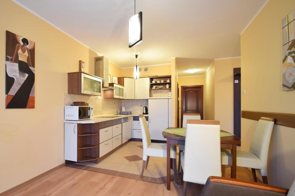 a kitchen and dining room with a table and chairs at Apartament 29 Zielone Tarasy Kołobrzeg in Kołobrzeg