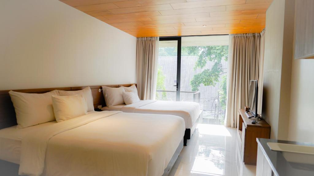 Nagomi Suites & Hotel في جاكرتا: سريرين في غرفة الفندق مع نافذة