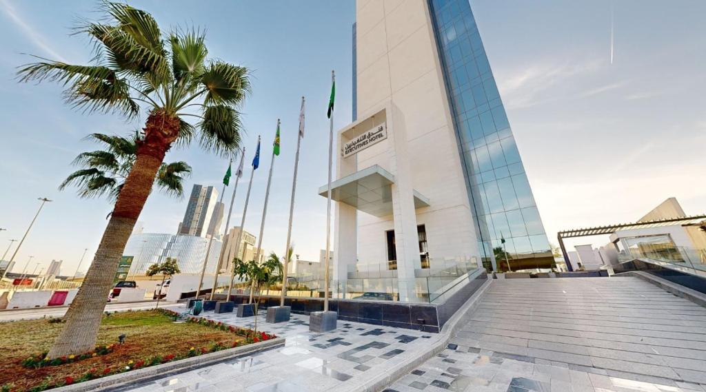 a building with a palm tree in front of it at Executives Hotel / KAFD in Riyadh