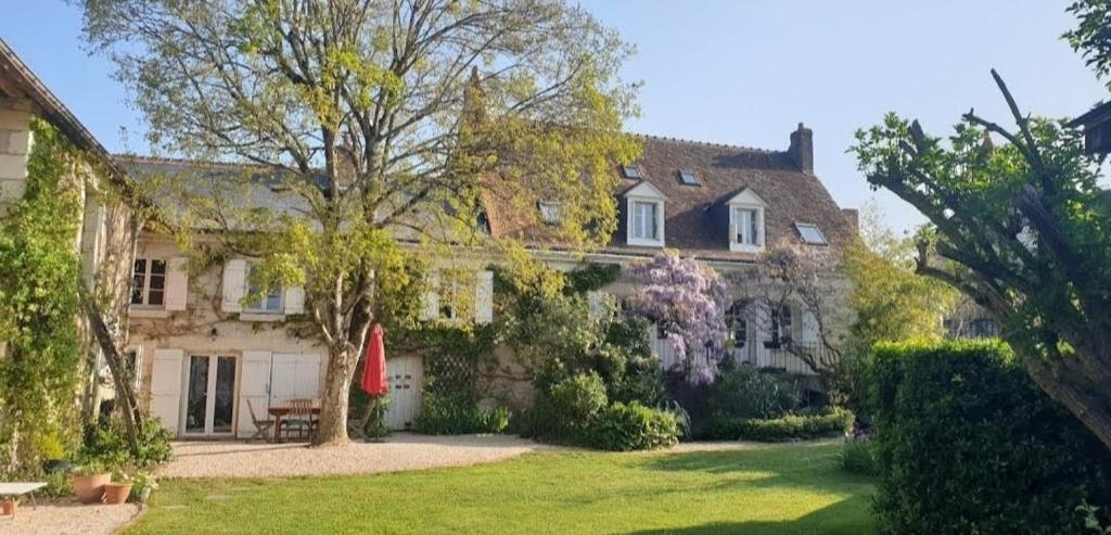 een groot stenen huis met een tuin met een boom bij Domaine Les Feuillants in Crouzilles