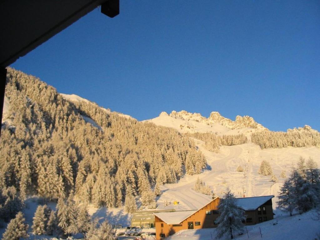 une maison dans la neige à côté d'une montagne dans l'établissement Résidence Gardette - 2 Pièces pour 4 Personnes 104, à Réallon