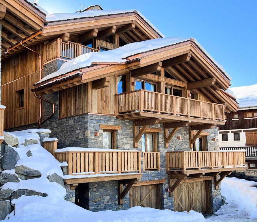 a log home with a deck in the snow at Résidence Nanook - Chalets pour 15 Personnes 444 in Saint-Martin-de-Belleville