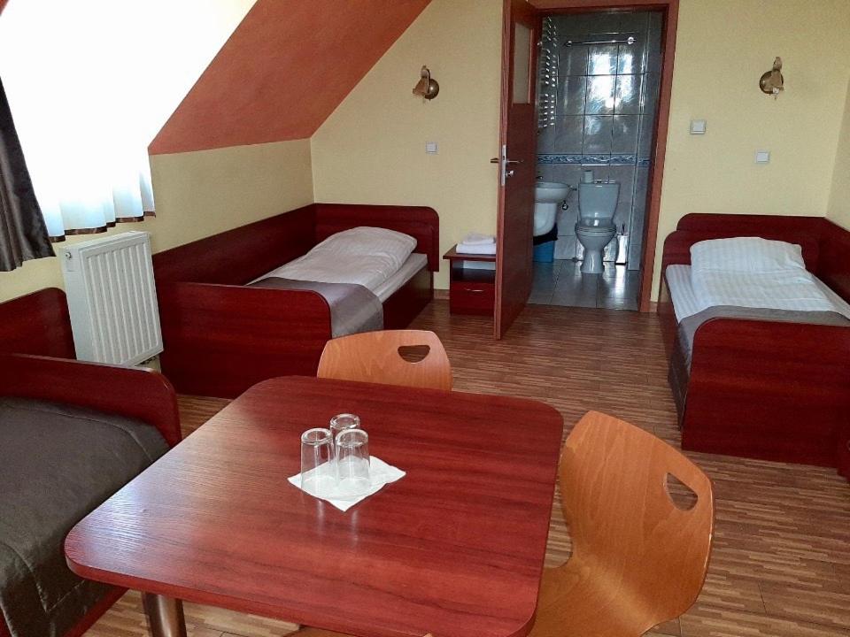 a room with two beds and a table with glasses on it at Motel Górno in Górno