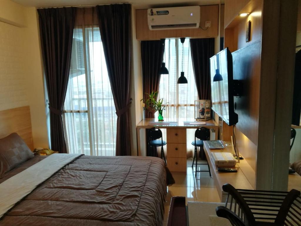 sypialnia z łóżkiem, biurkiem i oknami w obiekcie Studio Pleasant Tifolia w Dżakarcie