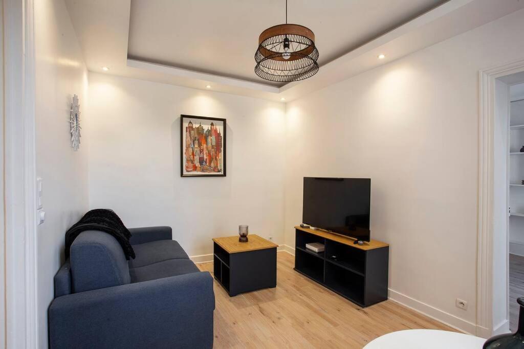 ein Wohnzimmer mit einem blauen Sofa und einem TV in der Unterkunft COSY, DESIGN AND LUXURY APARTMENT, 5 MINUTS PARIS in Saint-Mandé