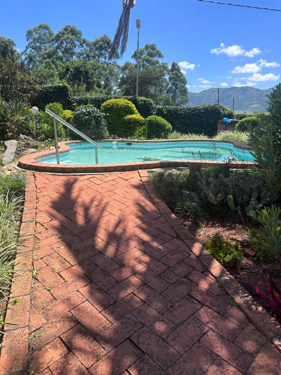 uma passagem de tijolos que leva a uma piscina em The White Rose Home em Lobamba