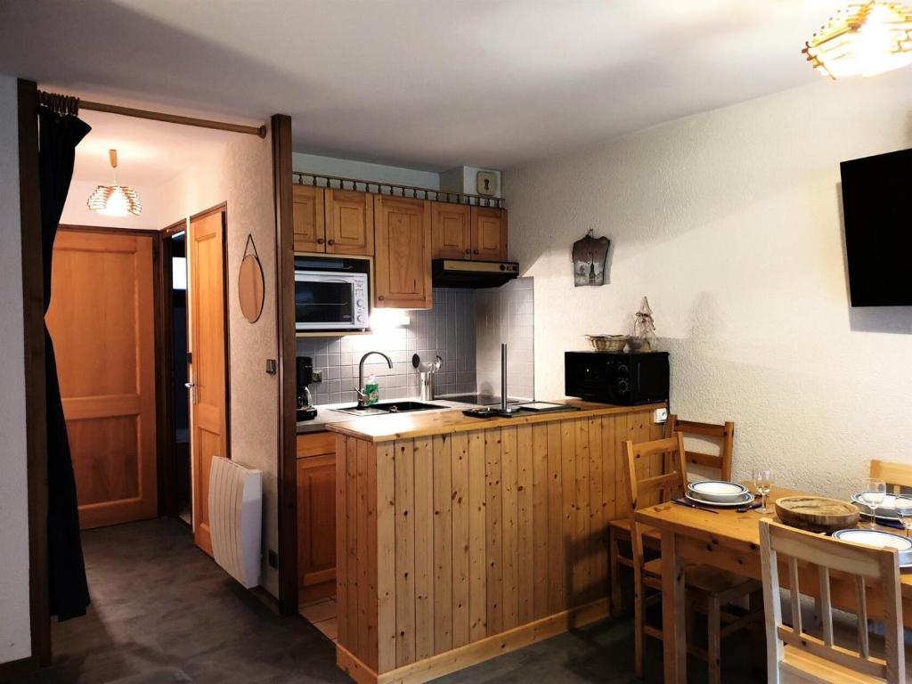 eine kleine Küche mit Holzschränken und einem Tisch in der Unterkunft Residence La Corniche - Studio pour 4 Personnes 154 in Morzine
