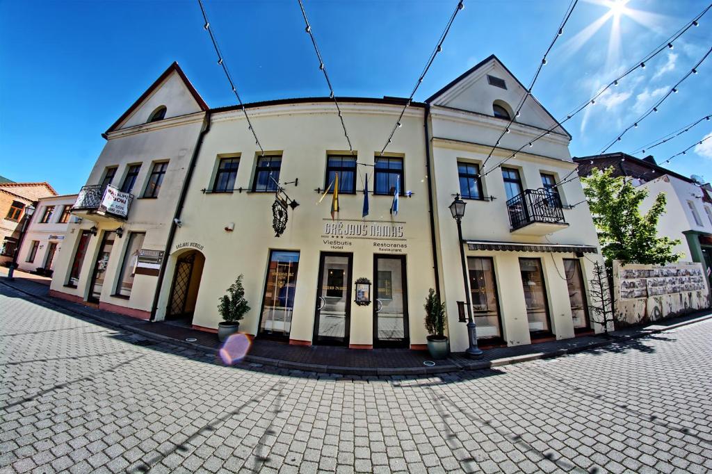 un gran edificio blanco en una calle de la ciudad en Grėjaus Namas en Kėdainiai