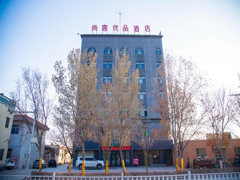 um edifício alto com um sinal em cima em Thank Inn Chain Kashgar Bachu Junmin Road Balchuk Town em Pa-ch'u-hsien