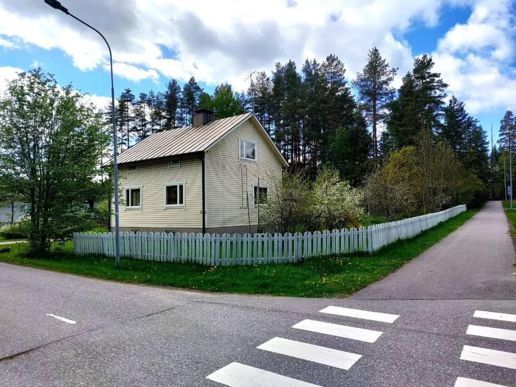 an old house with a fence on the side of a road at Nordic artist house/atelier with fireplace and old-fashioned wooden sauna from 50s in Heinola