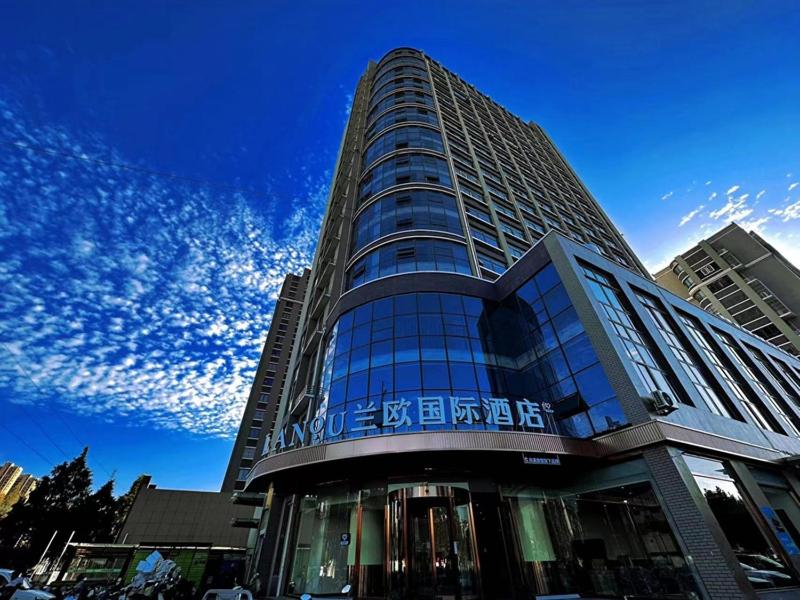 un edificio alto de cristal con un cielo azul en LanOu Hotel Lianyungang Donghai High-speed Railway Station Crystal City, en Donghai