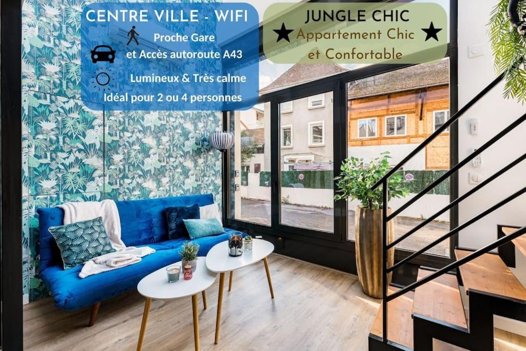 a living room with a blue couch and two tables at Bienvenue à Jungle Chic in Bourgoin