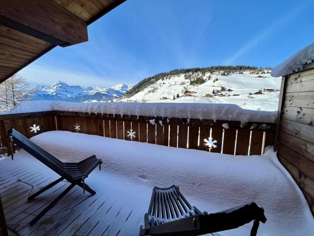 a snow covered deck with a bench and snow covered mountains at Résidence Res Cristal - 3 Pièces pour 4 Personnes 721 in Notre-Dame-de-Bellecombe