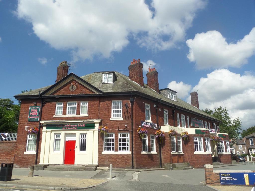 a brick building with a red door on a street at The Cabbage Hall Hotel in Liverpool