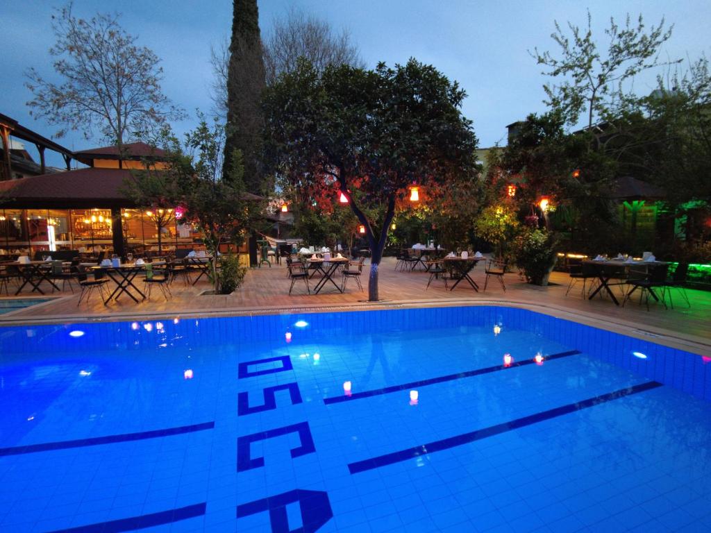 a swimming pool at night with tables and chairs at oscar garden hotel in Antalya
