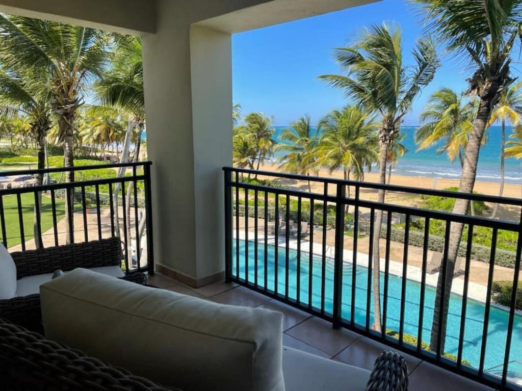 a room with a balcony with a view of the beach at Luxury Beachfront 2 Bedroom at Wyndham Rio Mar, PR in Luquillo
