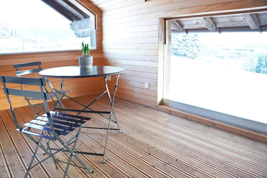 a table and chairs on a porch with a window at Landwohnung in Lingenau