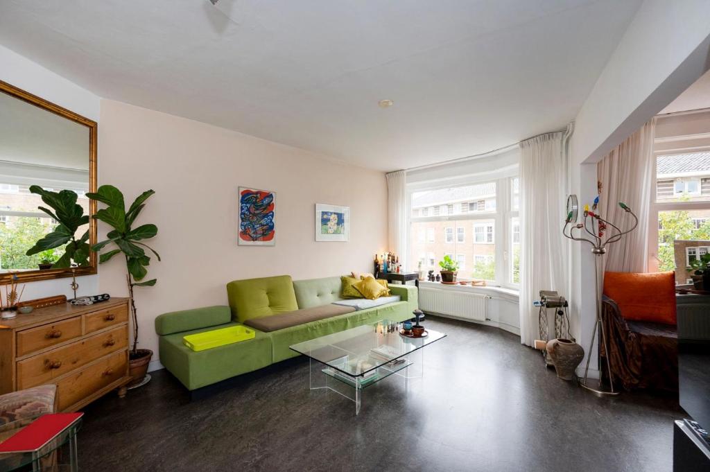 een woonkamer met een groene bank en een tafel bij Apartment Sandra in Amsterdam