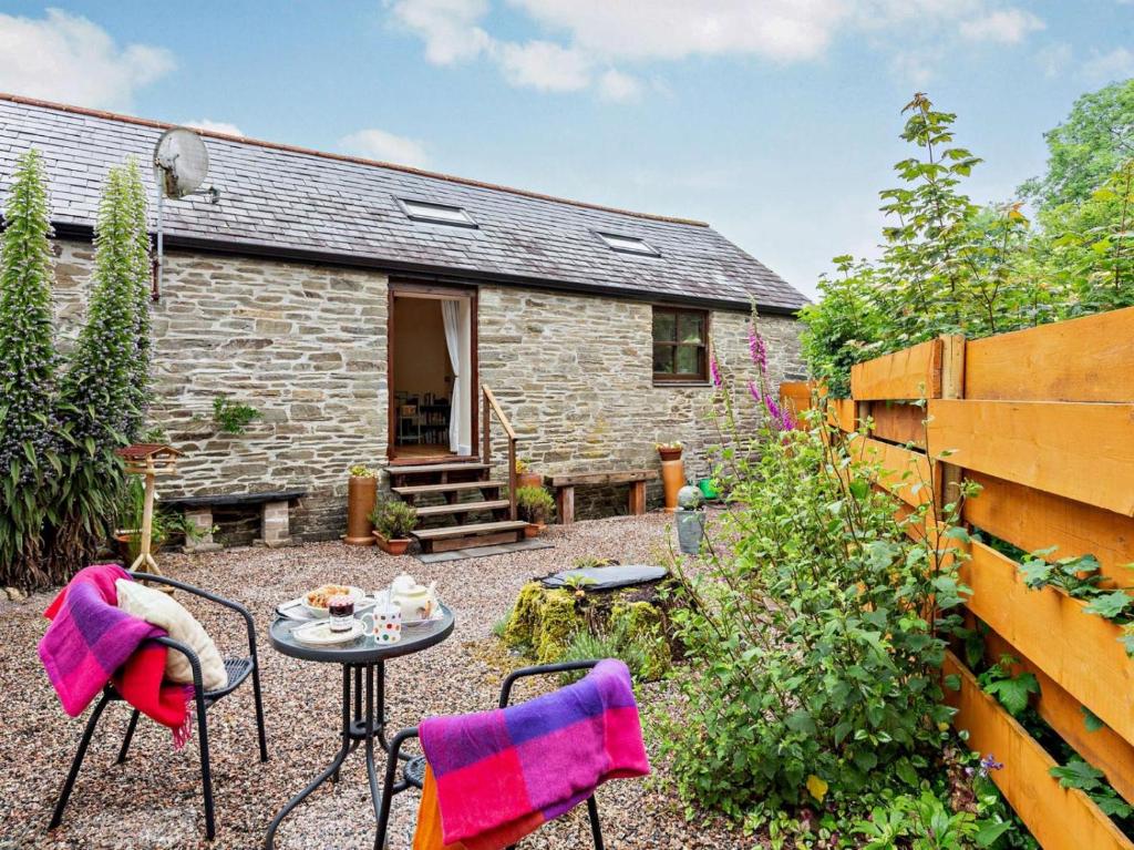 a stone cottage with a table and chairs in the yard at Tiptoe Barn in Liskeard