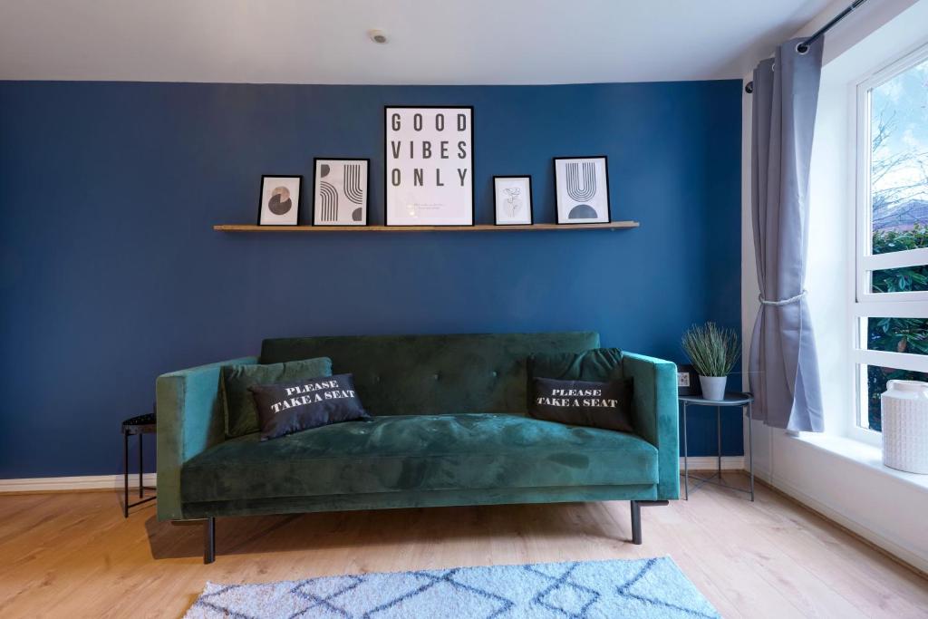 a green couch in a living room with a blue wall at Stylish Central Apartment with Free Parking, Fast WiFI and Smart TV by Yoko Property in Coventry