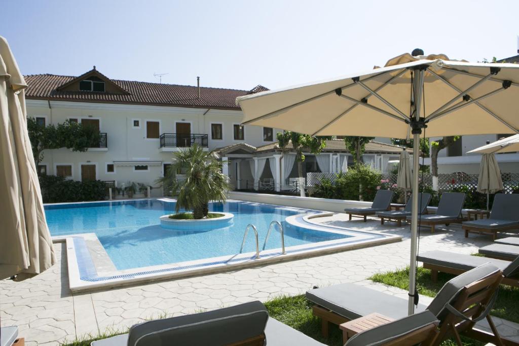 a pool with chairs and an umbrella next to a building at Hotel Rezi in Parga