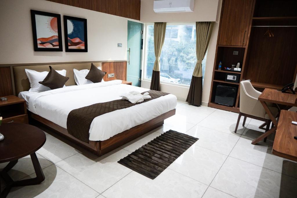1 dormitorio con 1 cama grande, mesa y escritorio en Hotel SUI en Guwahati