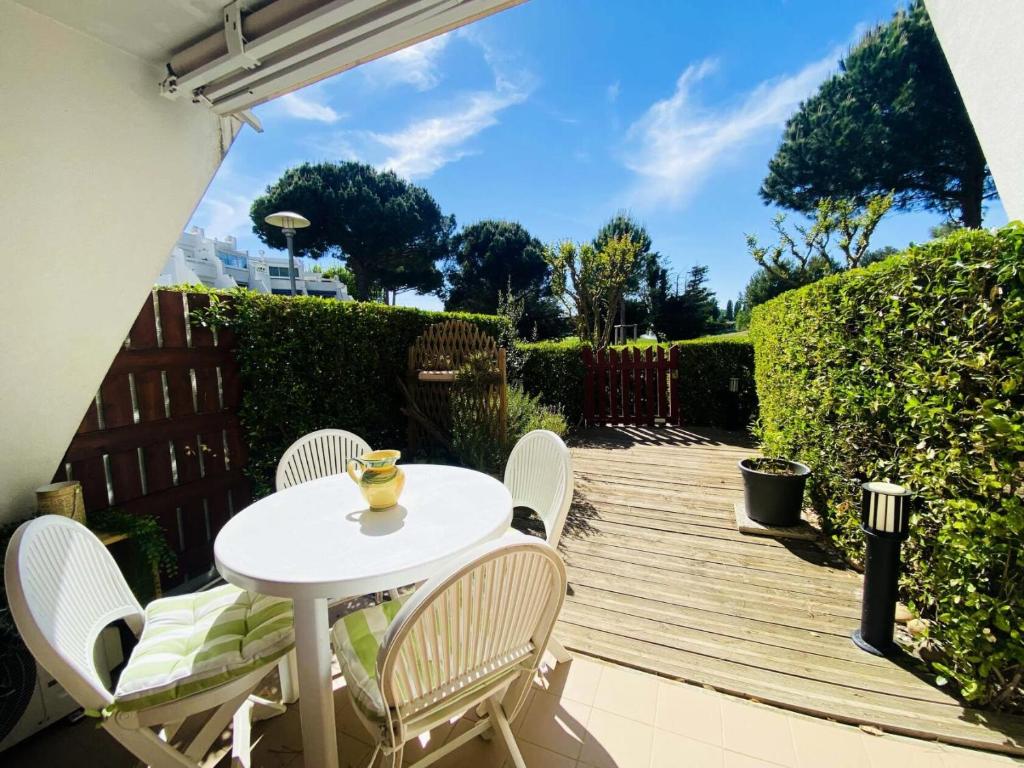 une table et des chaises blanches sur une terrasse en bois dans l'établissement Green Village - Deux pièces vue sur le golf 4 pers avec Clim MAE-0734, à La Grande Motte
