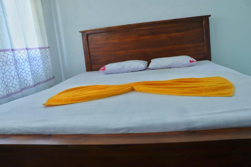 a bed with a blanket and two pillows on it at Warmy Treat Hotel in Kandy