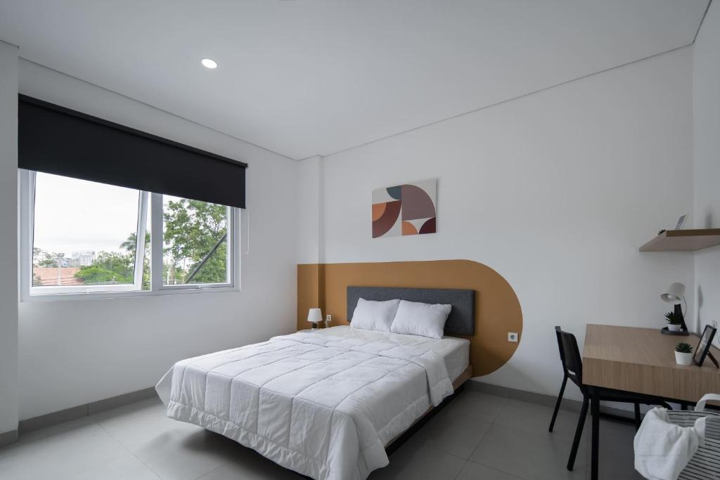 Dormitorio blanco con cama, mesa y ventana en Cove Nawaprita en Yakarta