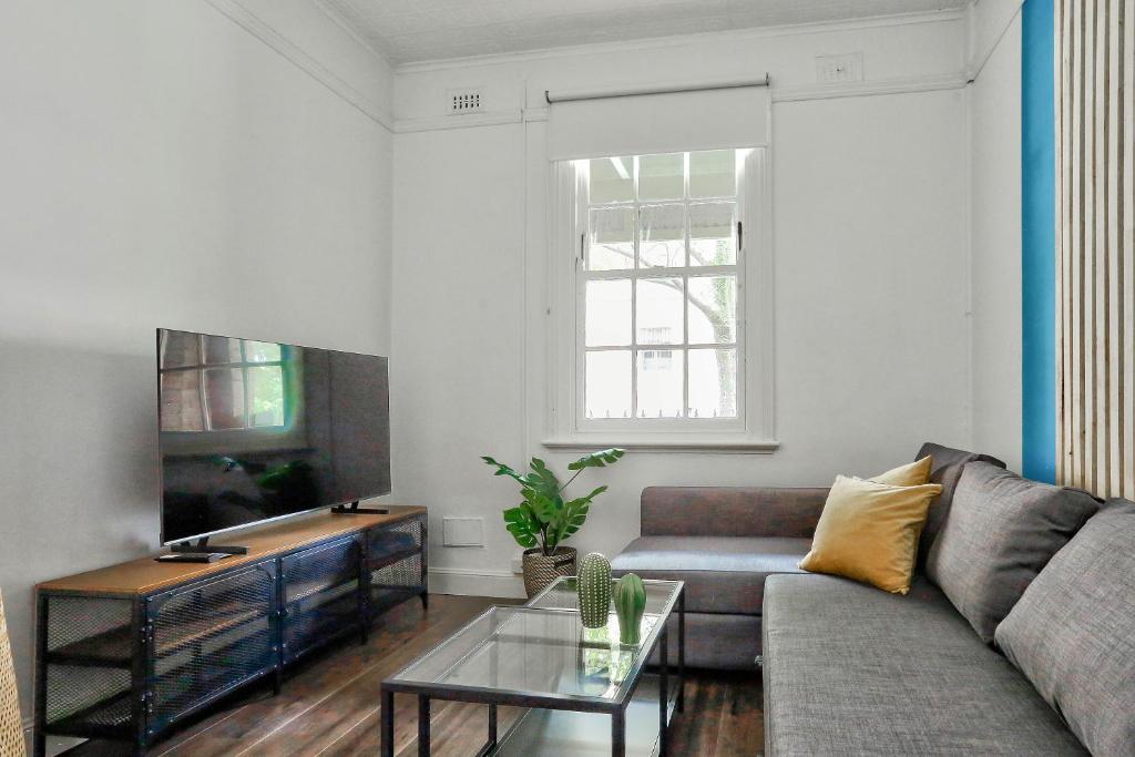 uma sala de estar com um sofá e uma televisão em Spacious 3 Bedroom House City Centre Millers Point 2 E-Bikes Included em Sydney